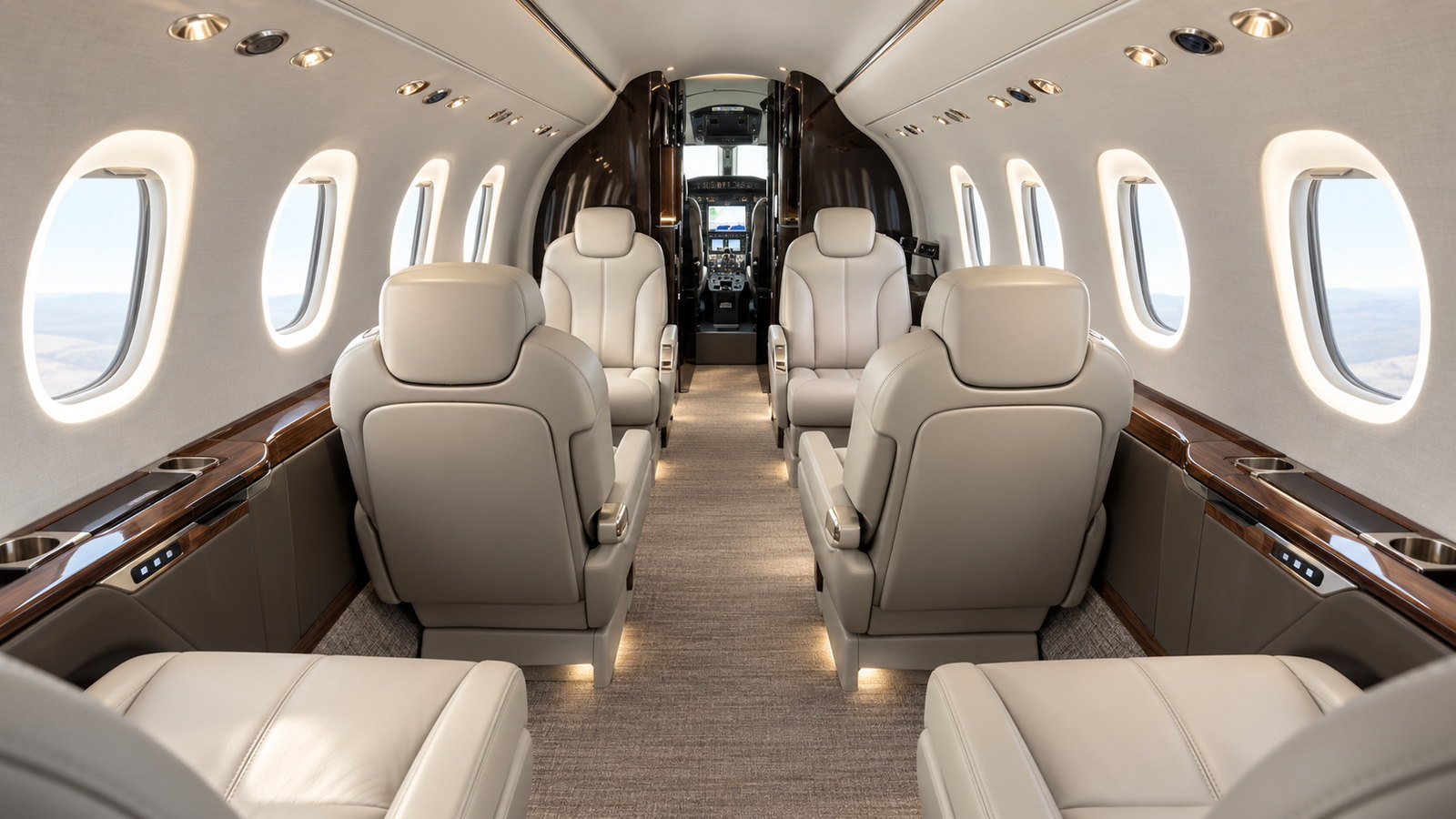 Citation Latitude cabin looking forward, four club seats in light leather with a fold out table