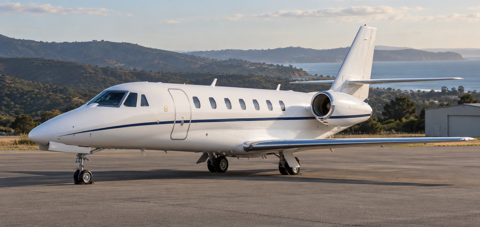 Cessna Citation Sovereign super midsize jet parked on an apron with hills and sea behind