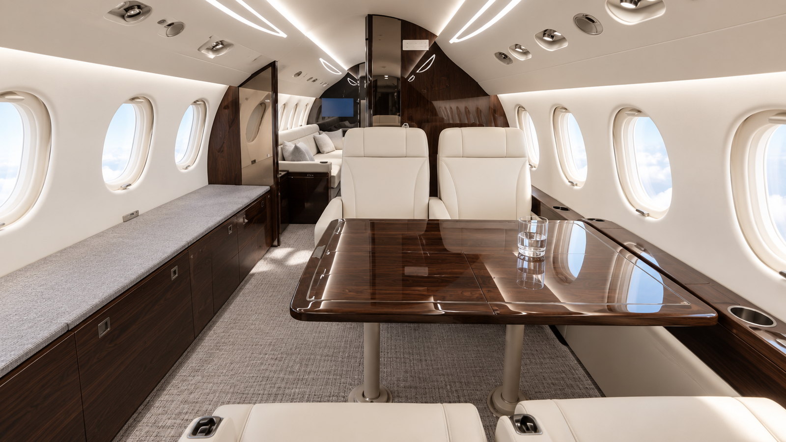 Falcon 7X cabin looking forward, four club seats and a dining table in dark wood