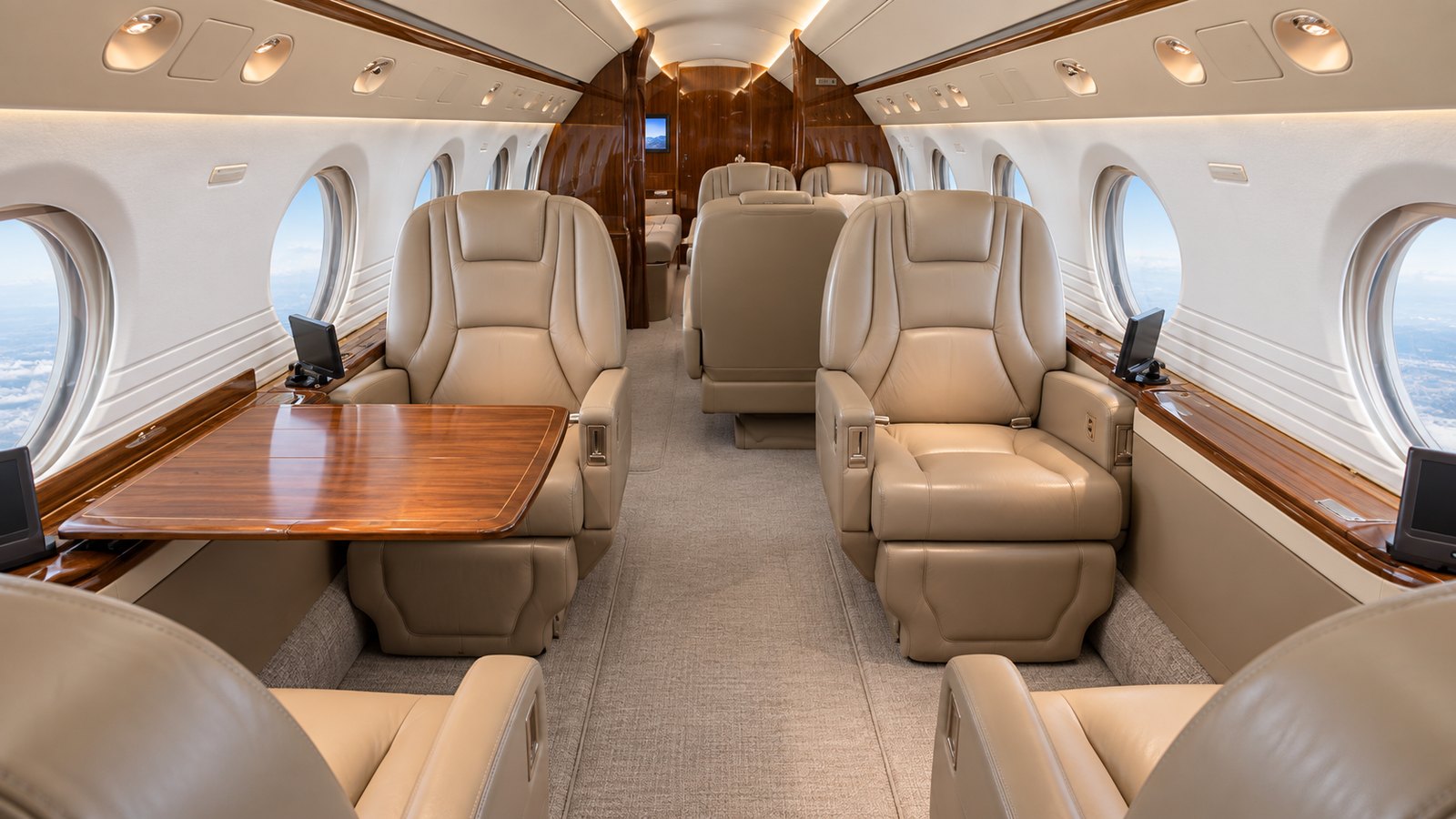 Gulfstream V cabin looking aft, single seats and a conference table in tan leather