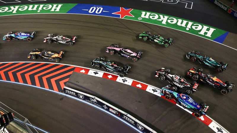 Formula 1 cars through a corner of the Las Vegas Strip circuit at night
