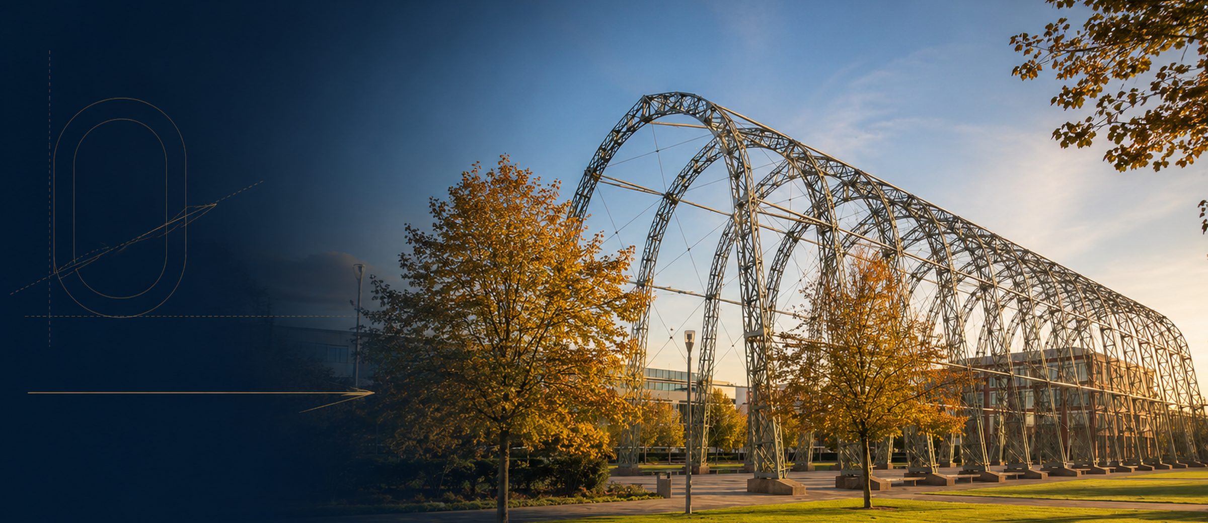 The steel arches of the former airship sheds at Farnborough, autumn trees and office buildings behind them