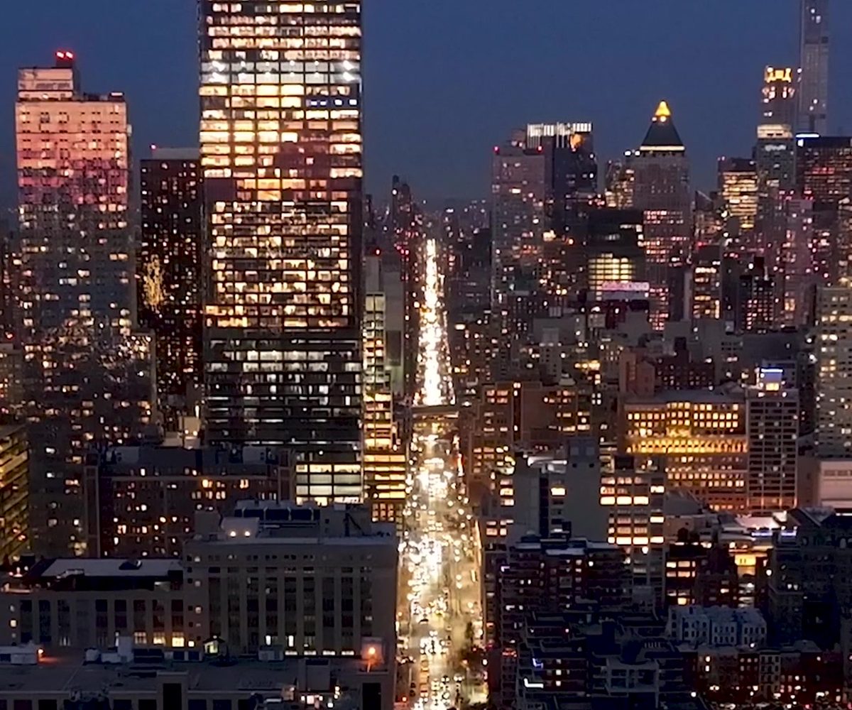 Midtown Manhattan towers lit at night, an avenue running away into the distance
