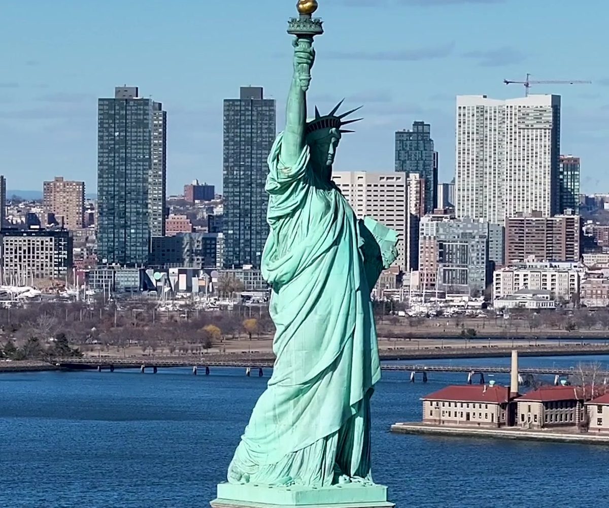 The Statue of Liberty on its pedestal seen from above, the Jersey City waterfront behind