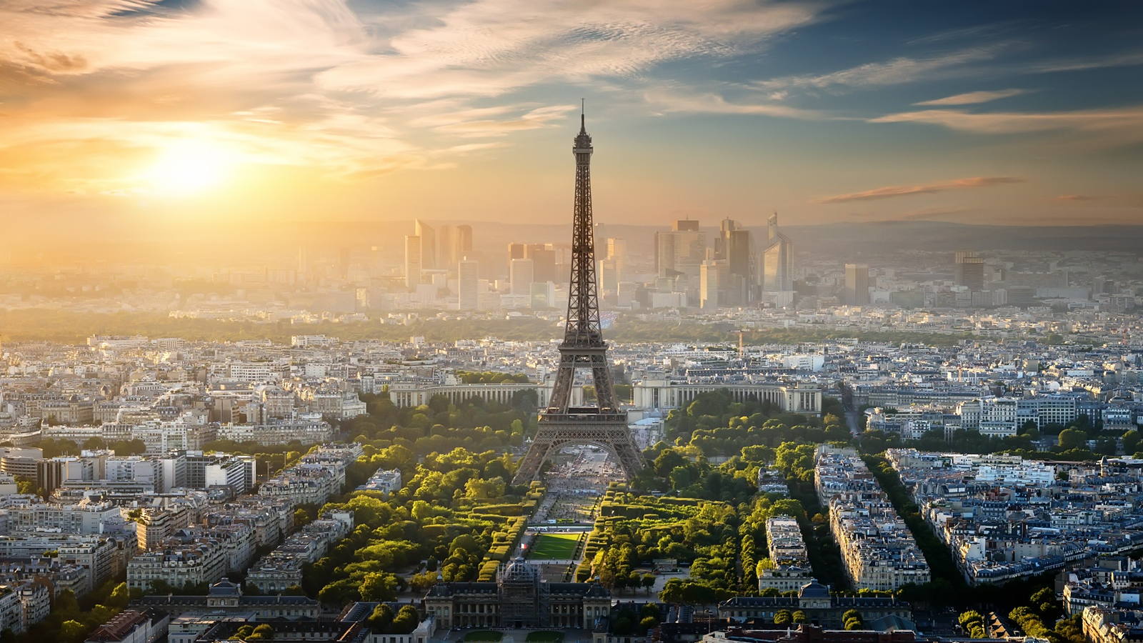 Paris at sunset from above, the Eiffel Tower over the Champ de Mars with La Defense on the horizon