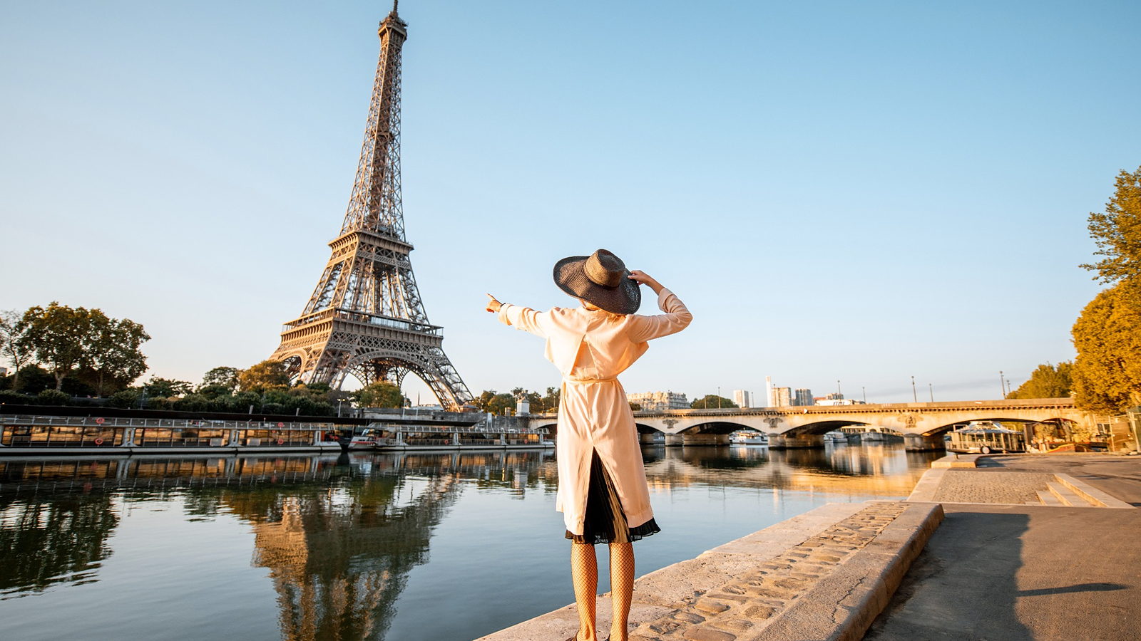 The Eiffel Tower reflected in the Seine in early morning light, seen from the riverside quay