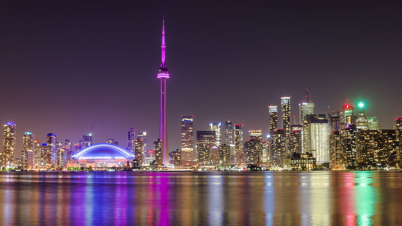 The Toronto skyline at night from Lake Ontario, with the CN Tower and Rogers Centre reflected in the water