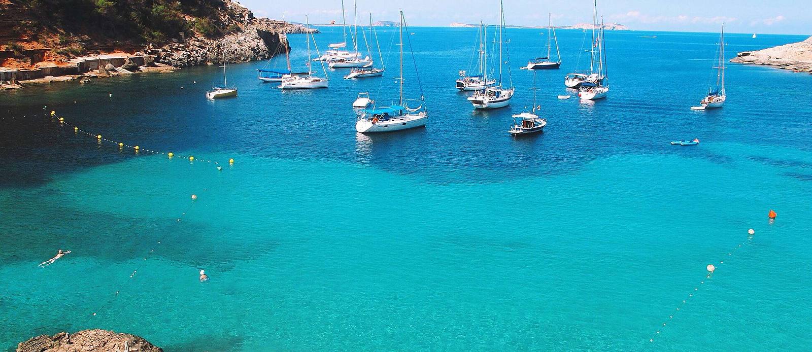 clear water and pine-covered cliffs on the Ibiza coast, on the Antwerp to Ibiza empty leg route